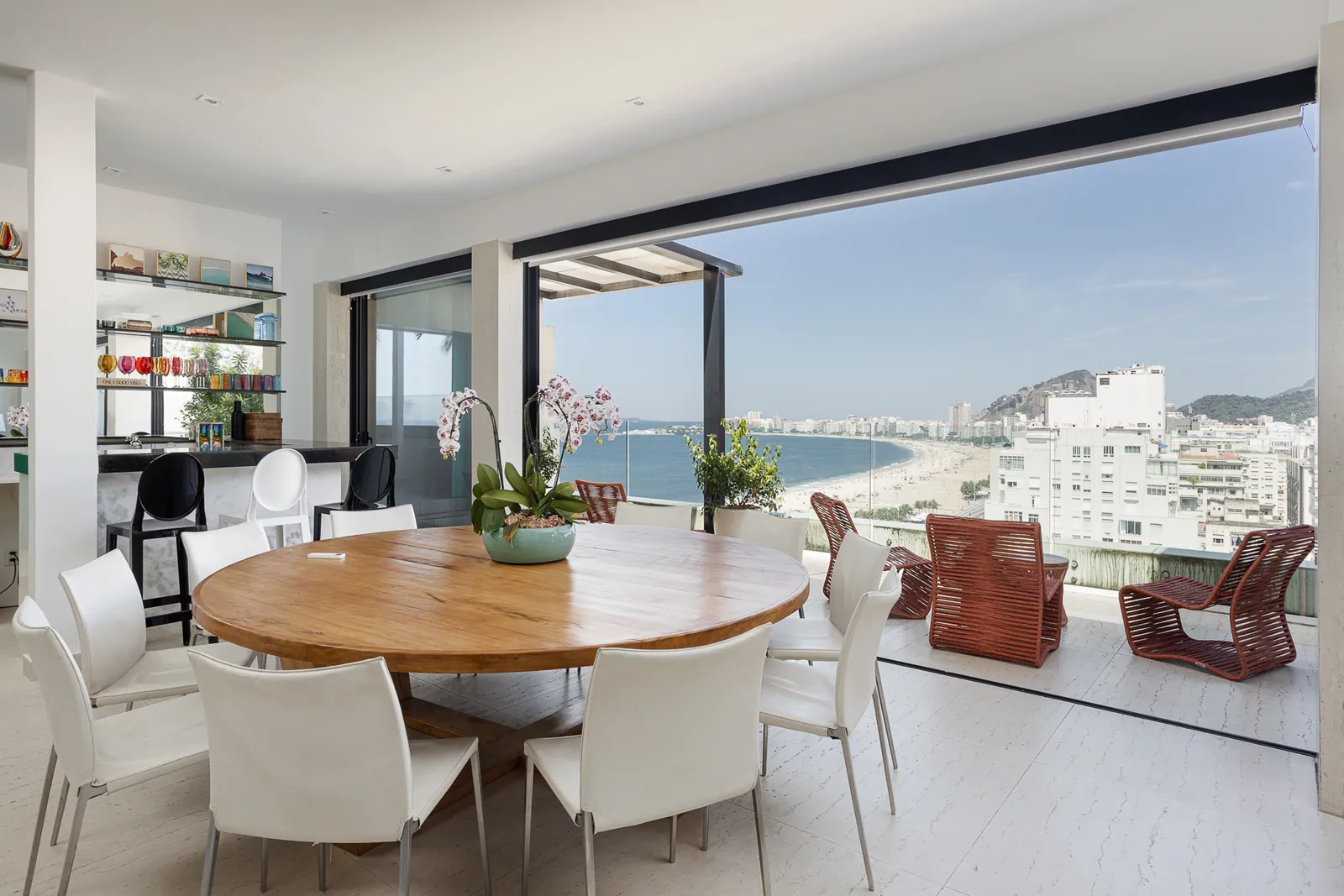 Open living and dining area with bookshelves and orchids